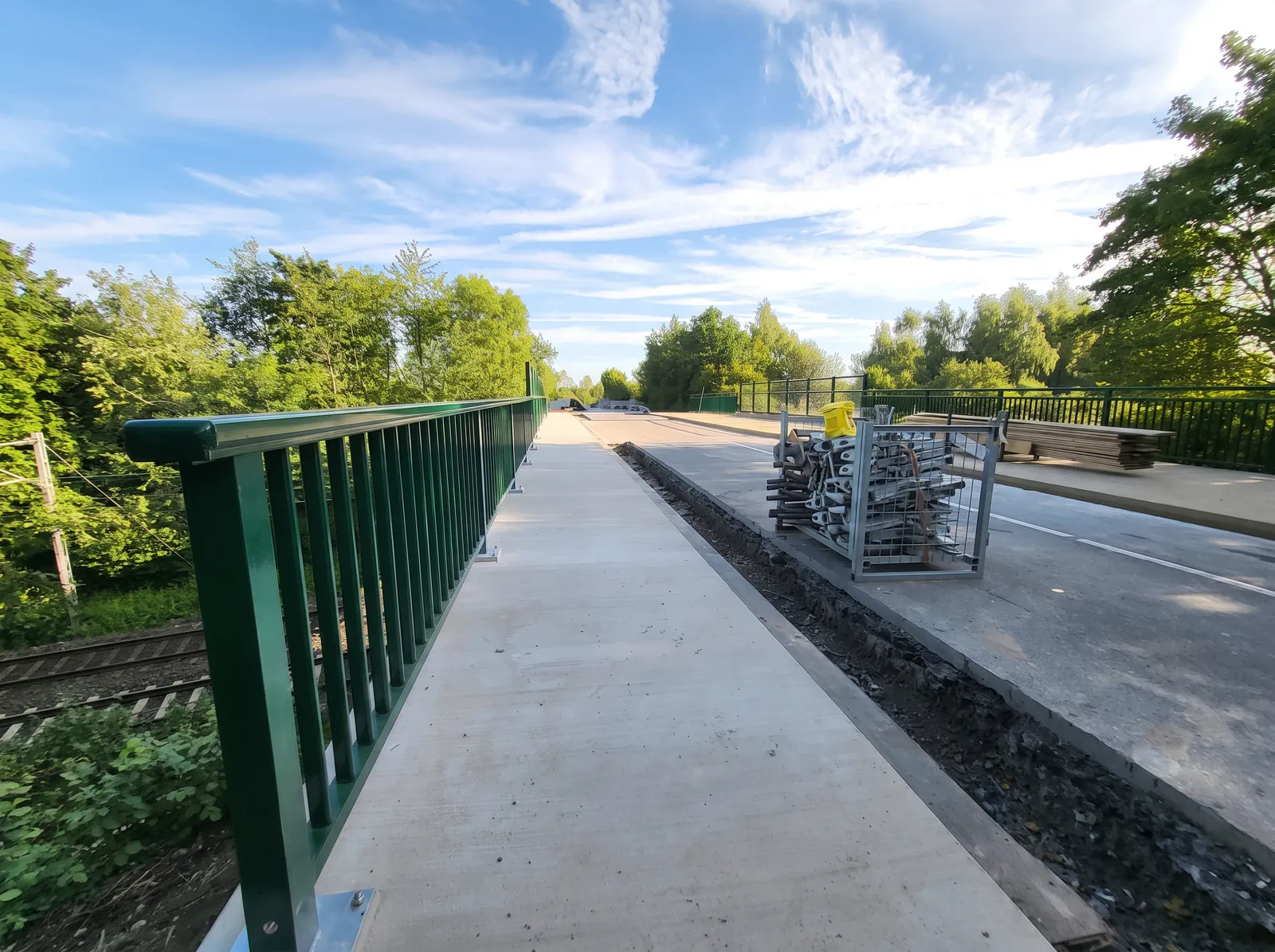 Neue Brückenkappe mit grünem Geländer und Gehweg über der Bahnstrecke